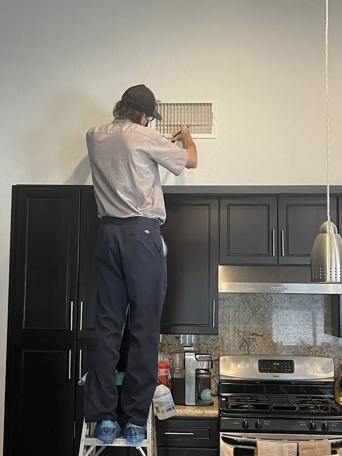 Technician inspecting an air vent during HVAC service in Tichigan